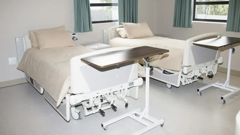 Chambre d'hôpital lumineuse avec deux lits médicalisés et leurs tablettes