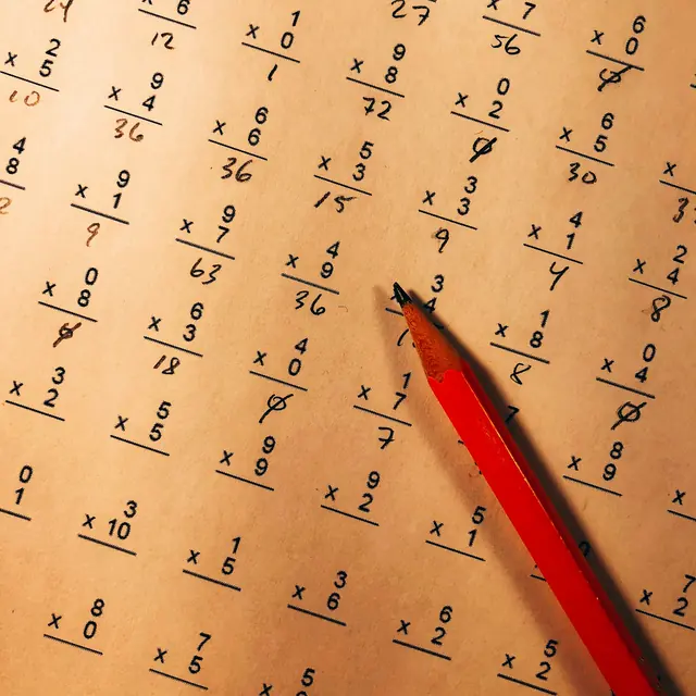 Crayon rouge posé sur une feuille d'exercices de multiplication