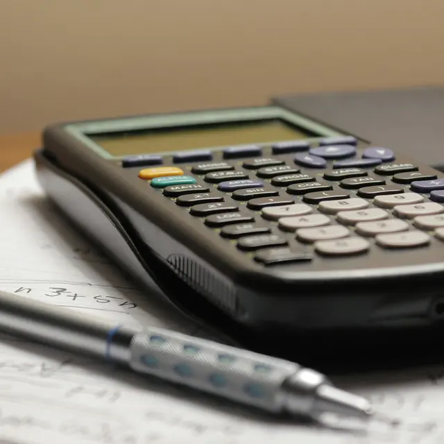 Calculatrice et stylo posés sur une feuille de calcul