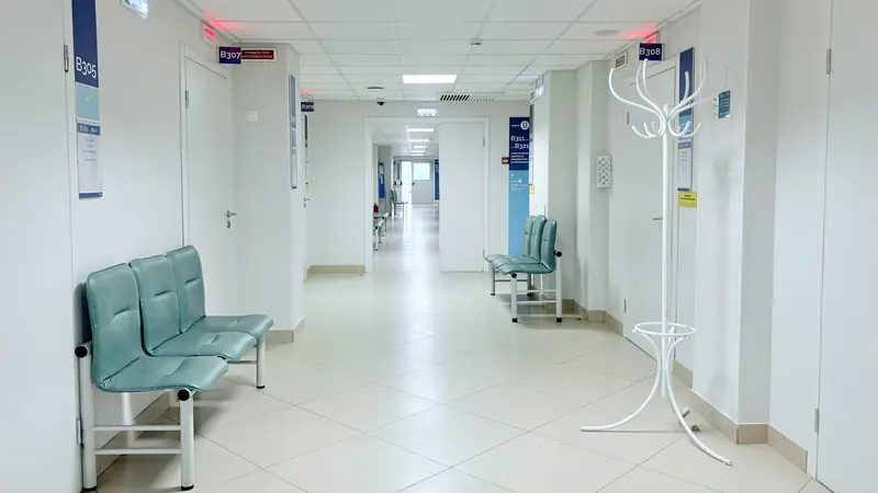 Couloir d'hôpital vide et lumineux, bancs le long du mur