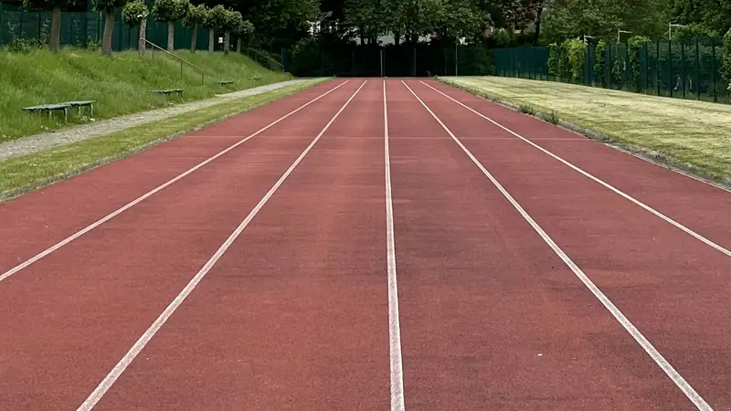 Couloirs d'une piste d'athlétisme en plein air, bordée d'arbres